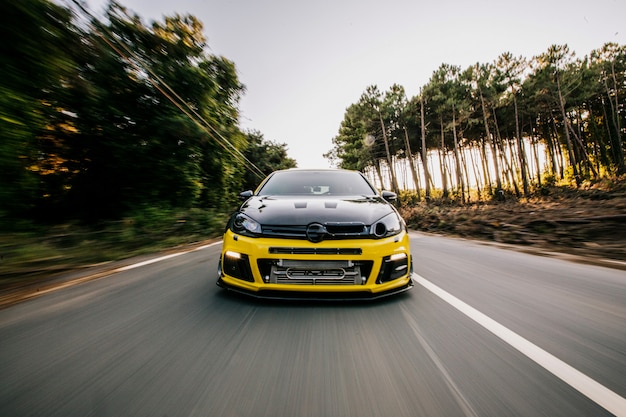 yellow-sport-car-with-black-autotuning-highway-front-view_114579-5060
